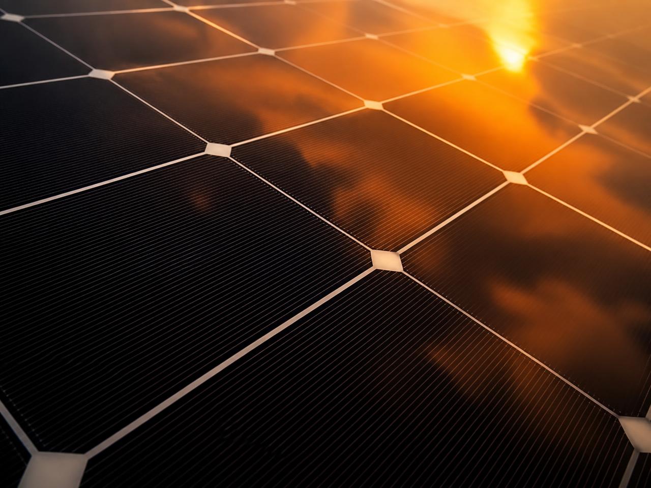 Close-up of a black solar panel reflecting a sunset sky
